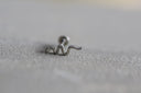 Silver snake-shaped earring on a textured grey surface