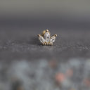 Single diamond earring on a dark textured surface
