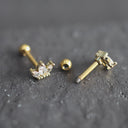 Three stone gold earrings on a textured black surface