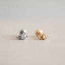 Two gold and silver earrings on a blurred background