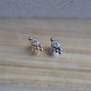 Pair of gold and silver stud earrings on a wooden surface