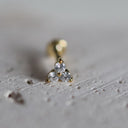 Gold earring with three diamonds on a textured surface