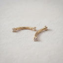Gold earrings with clear stones on a textured beige surface