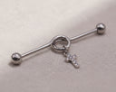 Silver Industrial Cartilage with a cross charm on a beige surface
