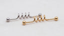 Two metallic barbells with spiral designs on a beige surface.