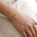 Gold initial bracelets with 'JAX' on a wrist against a neutral background