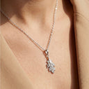 Silver leaf pendant necklace on a person wearing a beige coat