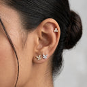 Close-up of an ear wearing butterfly-shaped earrings with a neutral background