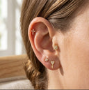 Close-up of an ear wearing multiple gold earrings with a blurred background
