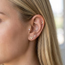 Close-up of an ear wearing gold earrings with small stones.