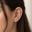 Close-up of an ear wearing gold and silver earrings with a neutral background