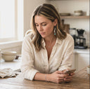 Woman using a smartphone in a kitchen setting. wearing Ella and Faith London Jewellery