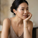 Woman wearing gold jewelry with a neutral background