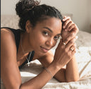 Woman with her hands clasped together on a bed