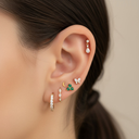 Close-up of an ear with multiple earrings on a neutral background