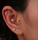 Close-up of an ear with multiple earrings including a gold crescent moon earring.