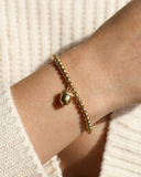Gold bracelet on a wrist with a textured white background