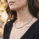 Sculpted Link Necklace – PVD Gold-Plated | Stainless Steel. Close-up of a person wearing a silver necklace with a blurred natural background