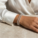 Close-up of a hand wearing multiple bracelets on a neutral background