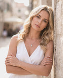 Woman in a white dress standing against a stone wall in an urban setting