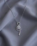 Silver necklace with a pendant on a grey fabric background