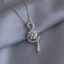 Silver necklace with a pendant on a grey fabric background