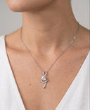 Silver necklace with a pendant worn by a person against a neutral background