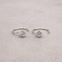 Pair of silver open hoop earrings with clear gemstones on a light gray background