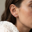 Close-up of a woman wearing gold and silver earrings with a neutral background