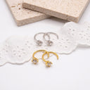 Gold and silver hoop earrings on a white lace fabric with a stone background