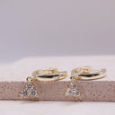 Mini Moissanite Drop Hoop Earrings- Three Stone Charm- Gold hoop earrings with small diamond-like stones on a textured surface