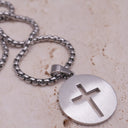 Engraved cross necklace featuring a circular stainless steel pendant with a cut-out cross design.