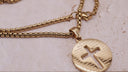 Engraved cross necklace featuring the Lord's Prayer on a gold circular pendant with a cut-out cross design.