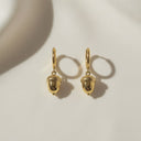 Gold Acorn Huggie Hoop Earrings showcasing delicate charm with polished gold finish on a soft background.