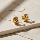 Chunky Link Huggie Hoop Earrings in gold stainless steel on a neutral surface, showcasing their bold design.