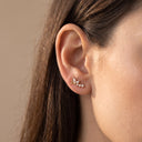A close-up of a woman's ear wearing Flora Vine CZ Cartilage Stud with small white gemstone accents, set against a soft beige background.