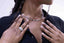 Close-up of a person wearing a silver ring and Sculpted Link Necklace in sliver-plated stainless steel. with hands touching the chest.