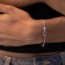 Infinity and Heart Moissanite, Rhodium-plated infinity charm with claw-set VVS moissanite on a fine silver chain bracelet.