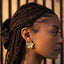 Close-up of a woman's profile with braided hair wearing Gold sculpted floral statement stud earrings 