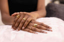 Close-up of hands with multiple gold rings on a white surface, also showing culpted Sparkle Adjustable Ring – 925 Silver, Hypoallergenic Fit.