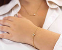 Mini CZ Bracelet – Gold PVD Plated Stainless Steel worn on a woman's wrist with a hand resting on a white shirt.