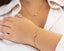 Gold bracelet worn on a wrist with a white shirt background