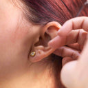Mini CZ Stud Earrings – 4mm Gold PVD Stainless Steel worn in a woman's ear, showcasing the brilliant round cut cubic zirconia.