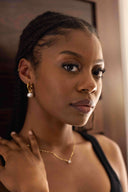 Woman with braided hair wearing earrings and a necklace indoors