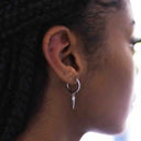 Close-up of an ear with a silver earring featuring a sharp design., 14K Gold-Plated CZ Pave Hoops – Chic Dagger Charm Earrings

Statement Sparkle | Lightweight | Hypoallergenic
