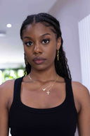Woman wearing a black tank top with gold jewelry indoors