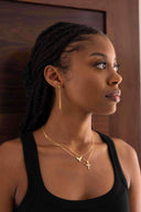 Woman wearing gold earrings and necklaces against a wooden background