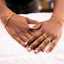 Close-up of two hands with gold jewelry on a white surface