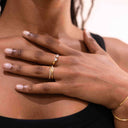 Hand with Twin Stone Sparkle Open Ring – Gold or Rhodium Plated on a blurred background
