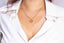 Initial Gold necklace with a heart pendant worn by a woman a white shirt.